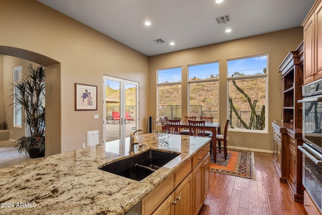 kitchen with a wealth of natural light, light stone counters, sink, and dark wood-type flooring