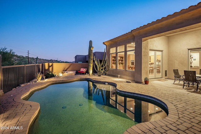 pool at dusk featuring a patio area and french doors