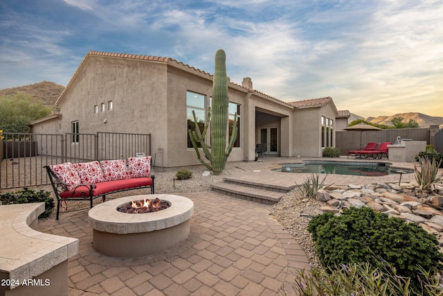 exterior space featuring a patio area, a pool with hot tub, and an outdoor living space with a fire pit