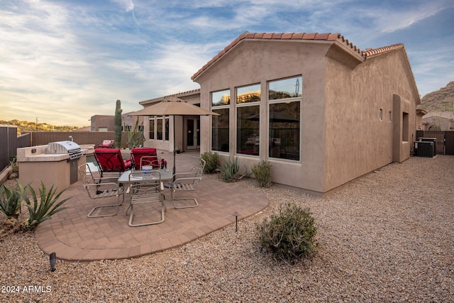 back house at dusk with central air condition unit and a patio