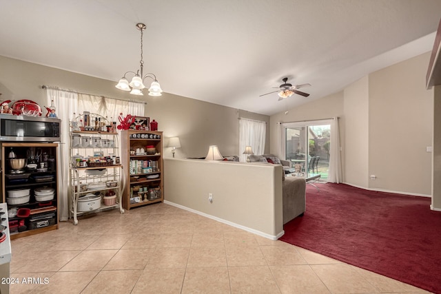 interior space featuring ceiling fan with notable chandelier, light tile patterned flooring, decorative light fixtures, and vaulted ceiling