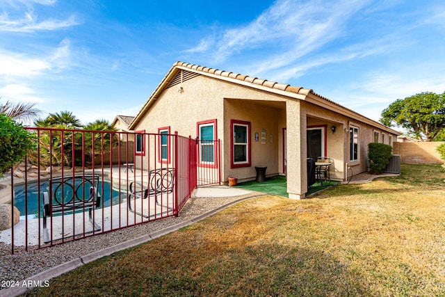 back of house featuring a fenced in pool, a patio area, and a lawn