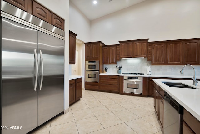 kitchen featuring light tile floors, high vaulted ceiling, sink, tasteful backsplash, and stainless steel appliances