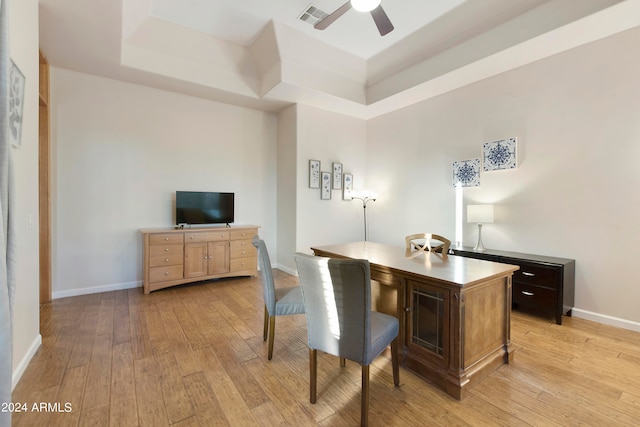 office featuring a tray ceiling, ceiling fan, and light hardwood / wood-style floors