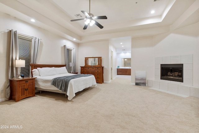 carpeted bedroom featuring connected bathroom, ceiling fan, a raised ceiling, and a fireplace