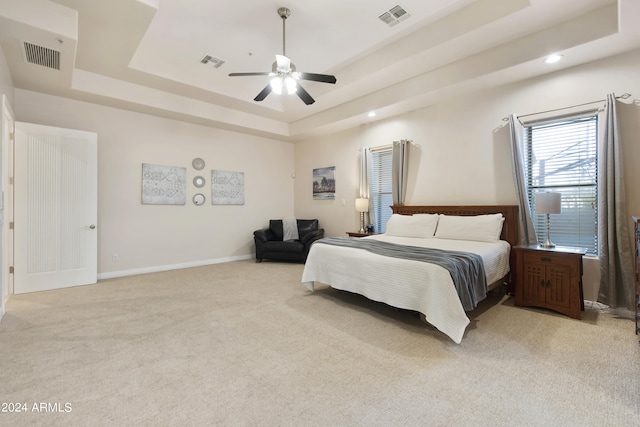 carpeted bedroom with ceiling fan and a raised ceiling