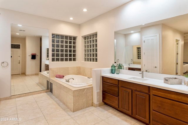 bathroom with tile flooring, vanity, and tiled bath