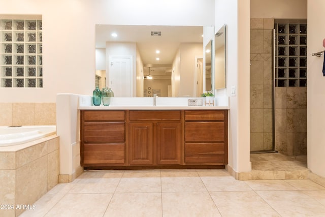 bathroom with tile flooring, vanity, and tiled tub