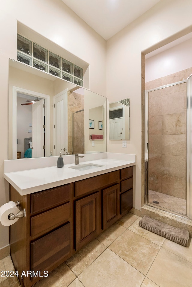 bathroom featuring a shower with shower door, ceiling fan, vanity, and tile floors