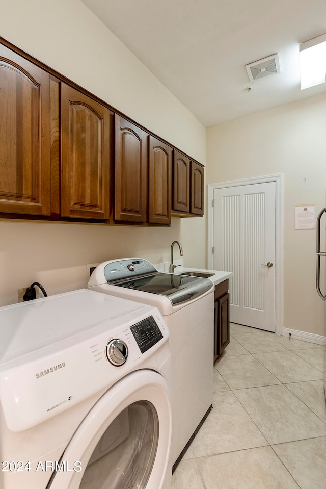 washroom with sink, cabinets, light tile floors, and separate washer and dryer