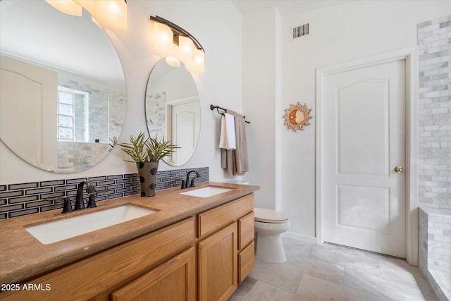 full bath featuring a sink, visible vents, toilet, and double vanity