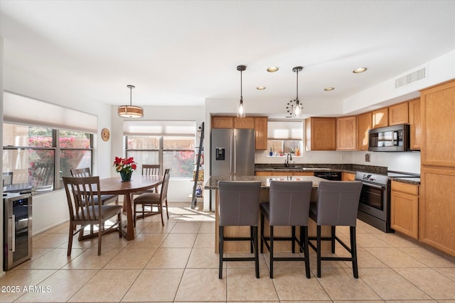 kitchen featuring visible vents, beverage cooler, dark countertops, appliances with stainless steel finishes, and light tile patterned floors