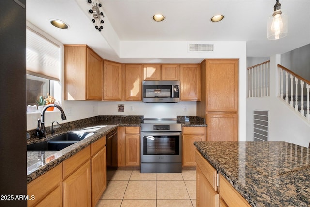 kitchen featuring visible vents, dark stone counters, light tile patterned floors, stainless steel appliances, and a sink