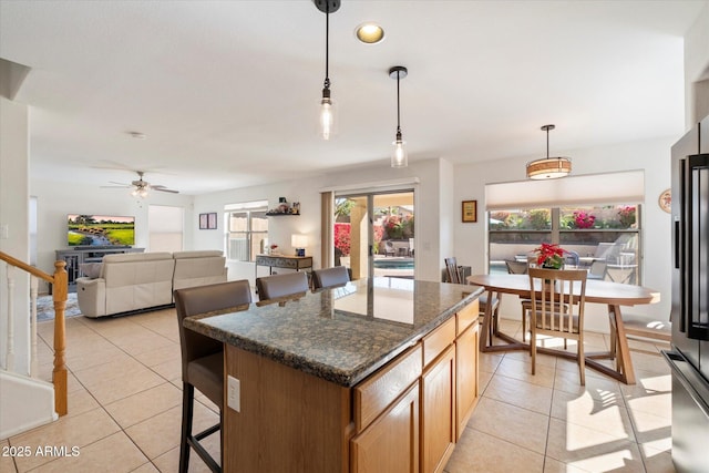 kitchen featuring pendant lighting, a kitchen breakfast bar, open floor plan, a center island, and light tile patterned flooring