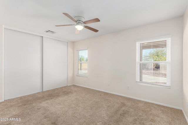carpeted empty room with visible vents and a ceiling fan