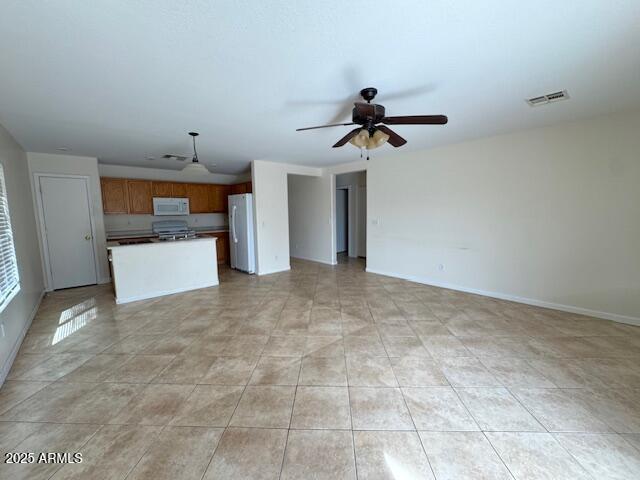 unfurnished living room featuring light tile patterned floors, a ceiling fan, visible vents, and baseboards