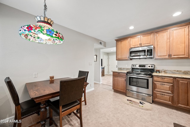 kitchen with appliances with stainless steel finishes and decorative light fixtures