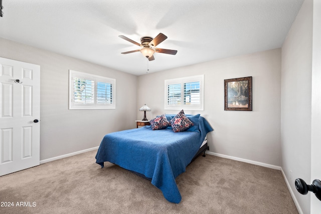 bedroom featuring light carpet, a textured ceiling, and ceiling fan