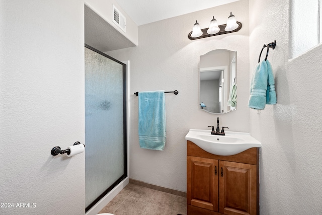 bathroom with a shower with door, vanity, and tile patterned floors