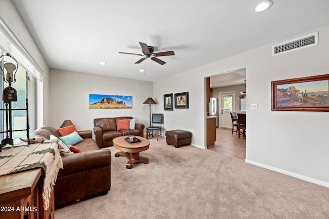 living room with a textured ceiling, light colored carpet, and ceiling fan