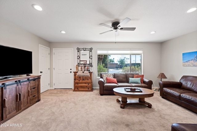 living room with a textured ceiling, light colored carpet, and ceiling fan