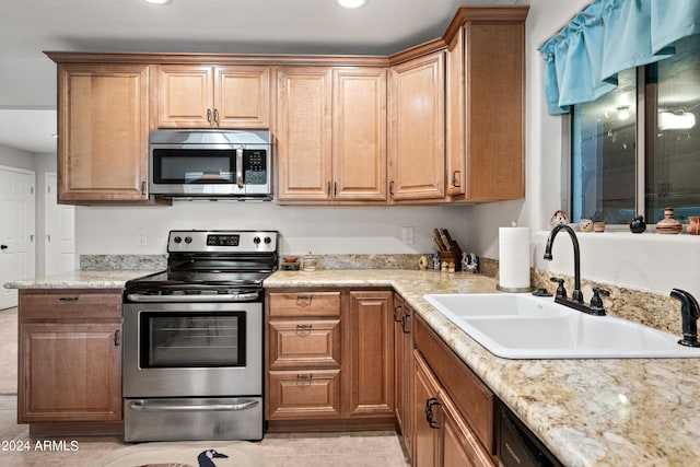 kitchen featuring sink, appliances with stainless steel finishes, light stone counters, and light tile patterned flooring