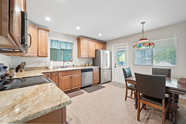 kitchen featuring light stone counters, stainless steel appliances, sink, and pendant lighting