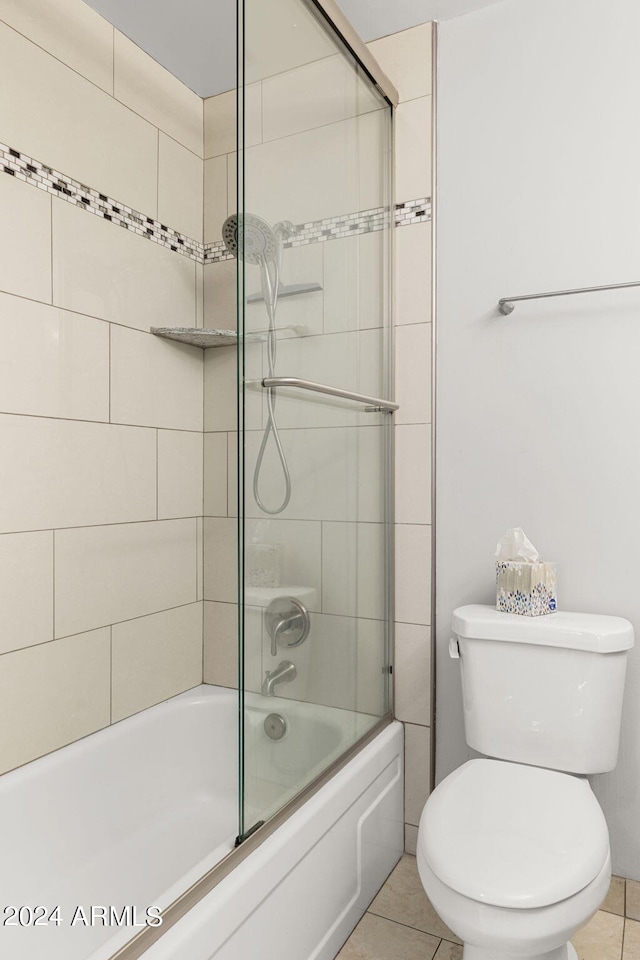 bathroom with tile flooring, combined bath / shower with glass door, and toilet