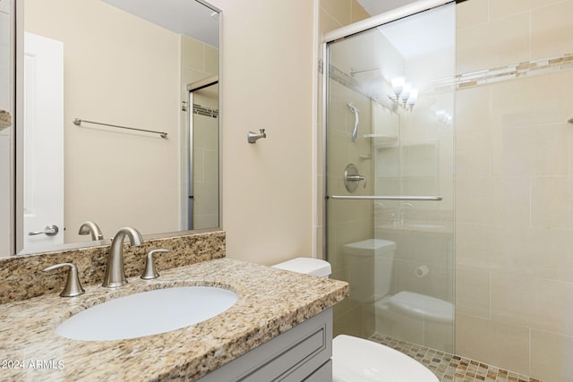 bathroom featuring toilet, large vanity, and a shower with shower door