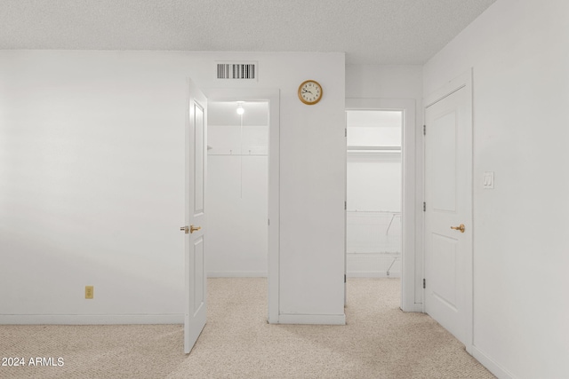 hallway featuring light carpet and a textured ceiling