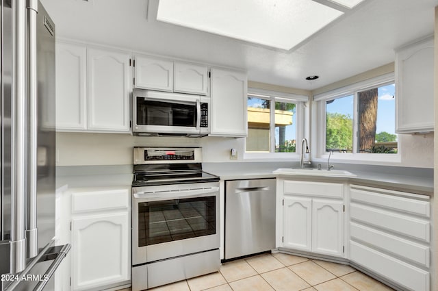 kitchen with light tile patterned flooring, appliances with stainless steel finishes, white cabinetry, and sink