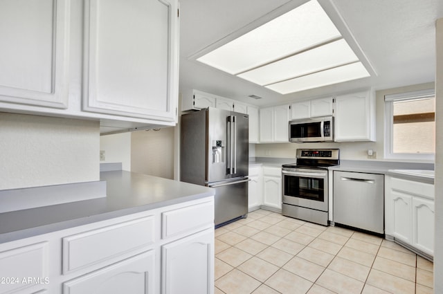 kitchen with stainless steel appliances, light tile patterned floors, and white cabinets