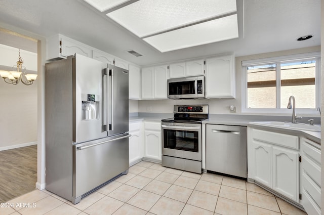 kitchen with an inviting chandelier, light hardwood / wood-style floors, stainless steel appliances, sink, and white cabinetry