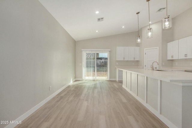 kitchen featuring white cabinetry, sink, high vaulted ceiling, light hardwood / wood-style floors, and decorative light fixtures