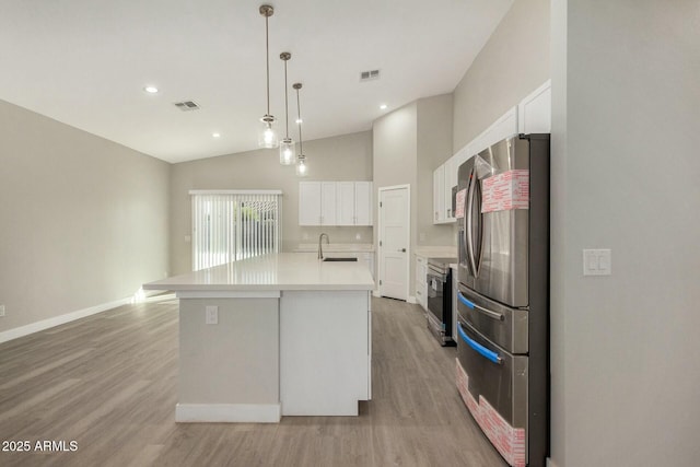 kitchen featuring stainless steel appliances, pendant lighting, a kitchen island with sink, white cabinets, and light wood-type flooring