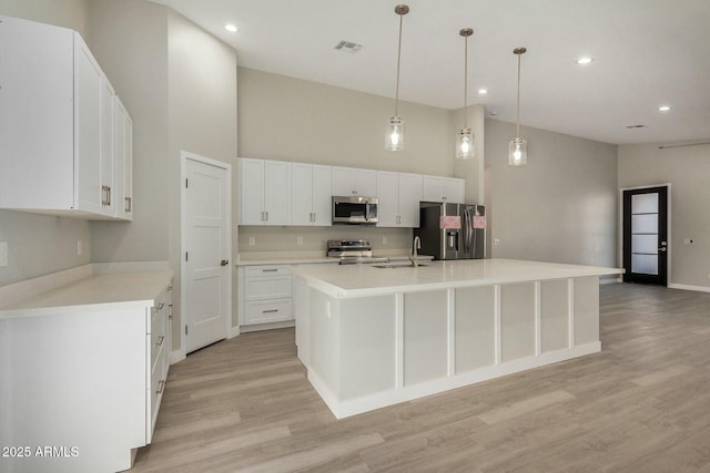 kitchen featuring sink, pendant lighting, a center island with sink, white cabinets, and appliances with stainless steel finishes