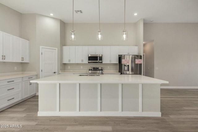 kitchen with a center island with sink, decorative light fixtures, sink, and stainless steel appliances