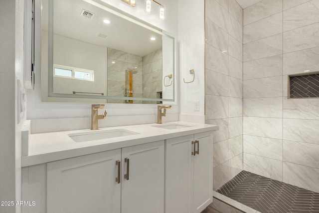 bathroom with tiled shower and vanity