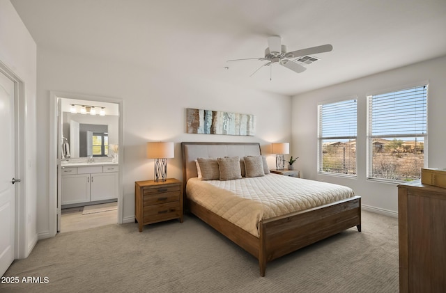 bedroom with light colored carpet, visible vents, baseboards, and ensuite bathroom