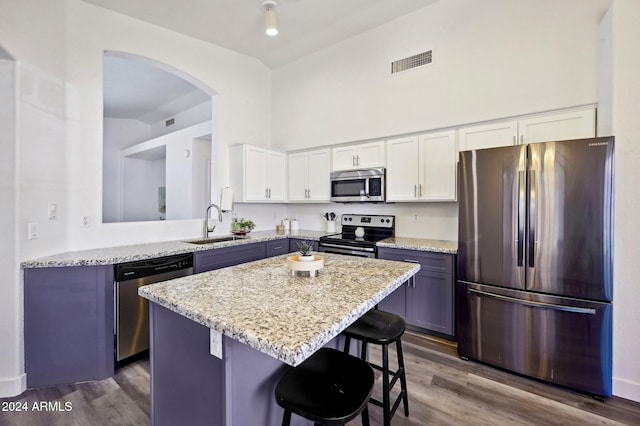 kitchen with a breakfast bar area, white cabinets, dark wood-type flooring, and appliances with stainless steel finishes