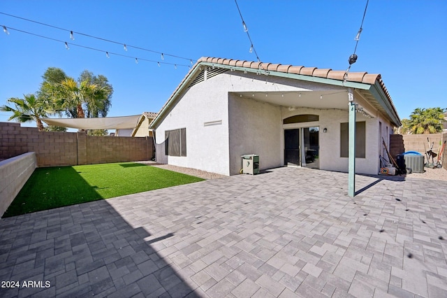 rear view of property featuring cooling unit, a yard, and a patio