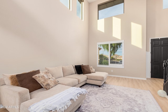 living room featuring light wood-type flooring and a towering ceiling