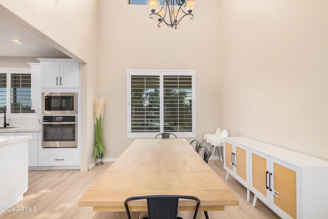 dining space with light hardwood / wood-style flooring, sink, and a notable chandelier