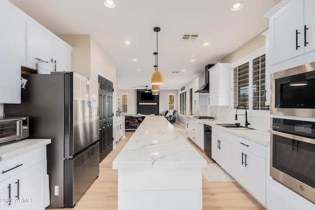 kitchen with sink, appliances with stainless steel finishes, light wood-type flooring, and a center island