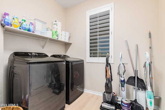 clothes washing area with washer and clothes dryer and light hardwood / wood-style flooring