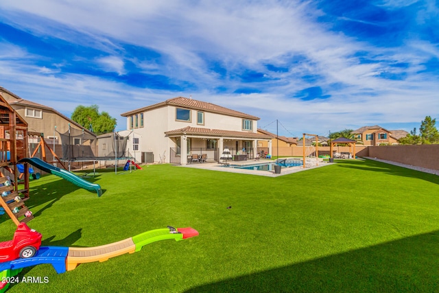 back of house with a patio area, a yard, cooling unit, a fenced in pool, and a trampoline