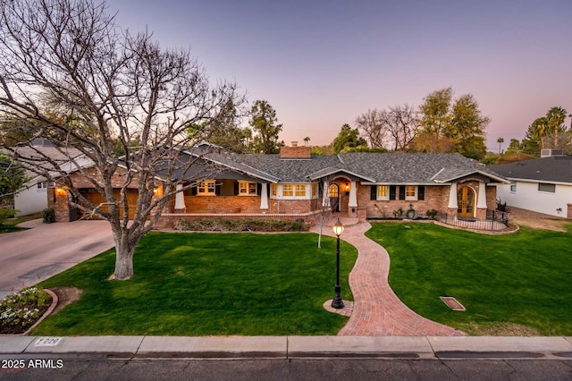 ranch-style home featuring a front lawn, decorative driveway, a chimney, and brick siding