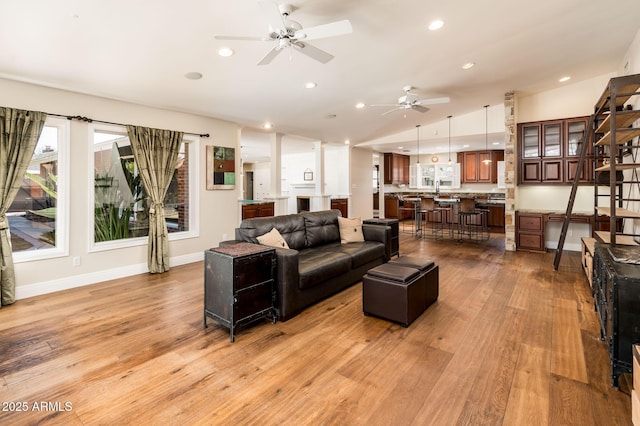 living room with ceiling fan, light wood-style flooring, recessed lighting, baseboards, and vaulted ceiling