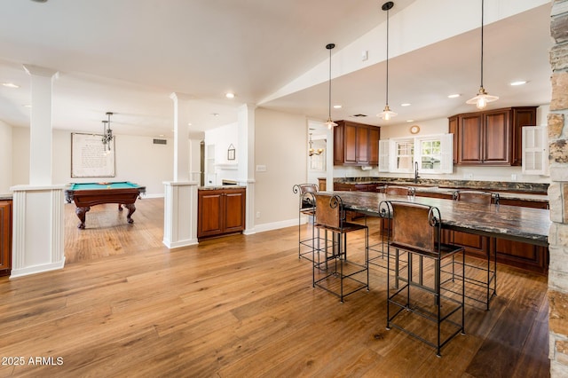 kitchen featuring pool table, a breakfast bar area, light wood-style flooring, and decorative light fixtures