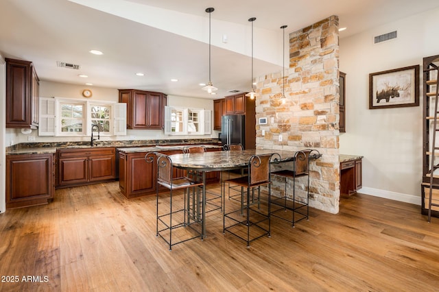 kitchen featuring a peninsula, high quality fridge, visible vents, and light wood-style floors